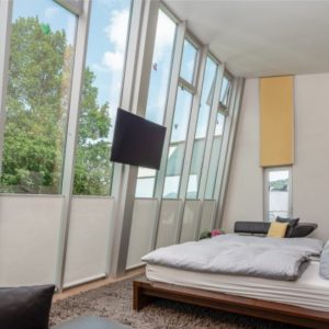Schlafzimmer mit bodentiefer Glasfront und Landschaftsblick | Bedroom with Floor-to-Ceiling Glass Front and Scenic View